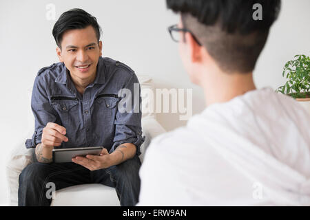 Men using digital tablet in living room Banque D'Images