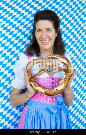 Femme dans un dirndl holding un gros bretzel Banque D'Images