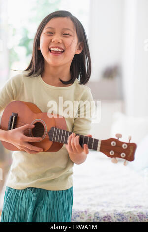 Jeune chinoise pratiquant ukulele dans la chambre Banque D'Images