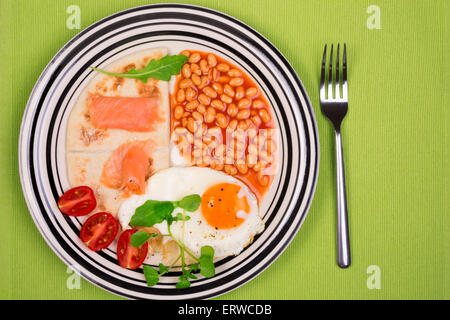 Assiette petit-déjeuner avec des oeufs frits, haricots blancs, pommes de terre et les scones de saumon écossais fumé au-dessus Banque D'Images