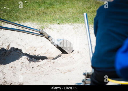 Enfant jouant avec metal digger à l'aire de jeux pour enfants dans le sable Banque D'Images