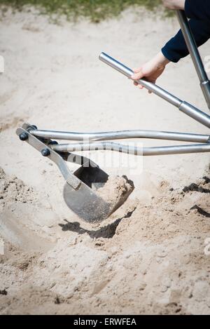 Enfant jouant avec metal digger à l'aire de jeux pour enfants dans le sable Banque D'Images