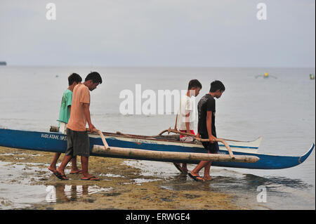 Les jeunes hommes exerçant son bateau de pêche pour l'eau à Panagsama Beach Philippines Moalboal Banque D'Images