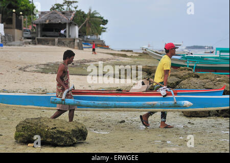 Les jeunes hommes exerçant son bateau de pêche pour l'eau à Panagsama Beach Philippines Moalboal Banque D'Images