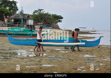 Les jeunes hommes exerçant son bateau de pêche pour l'eau à Panagsama Beach Philippines Moalboal Banque D'Images