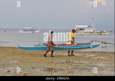 Les jeunes hommes exerçant son bateau de pêche pour l'eau à Panagsama Beach Philippines Moalboal Banque D'Images