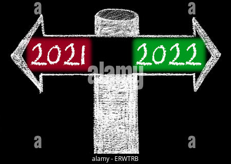 Flèches opposées à l'année 2021 en fonction de l'année 2022. Dessin à la main avec de la craie sur tableau noir. Choix de l'image conceptuelle Banque D'Images