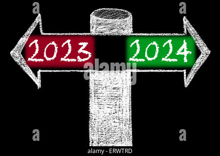 Flèches opposées à l'année 2023 en fonction de l'année 2024. Dessin à la main avec de la craie sur tableau noir. Choix de l'image conceptuelle Banque D'Images