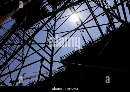 Shot industriel avec construction worker silhouetté contre le ciel bleu de travailler sur un échafaudage Banque D'Images