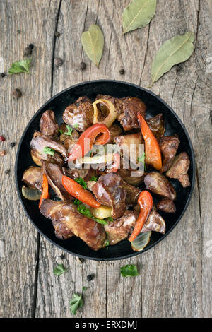 Foie de poulet grillé avec du poivre rouge dans une poêle sur une table en bois, vue du dessus Banque D'Images