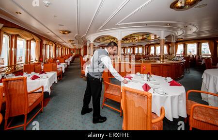 Kiel, Allemagne. 09Th Juin, 2015. Un membre d'équipage se tient dans le restaurant gastronomique sur le 'MS Deutschland' à Kiel, Allemagne, 09 juin 2015. Le navire, rendu célèbre par la série télévisée 'Das Traumschiff' (lit. Le navire de rêve), décolle aujourd'hui pour sa dernière croisière voyage sous commandement allemand. Dpa : Crédit photo alliance/Alamy Live News Banque D'Images