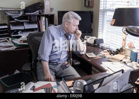 Businessman in Hoarders' Messy Home Office, USA Banque D'Images
