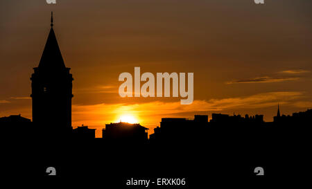 Silhouette de la tour de Galata à Istanbul au coucher du soleil avec le soleil juste derrière les bâtiments de la ville Banque D'Images