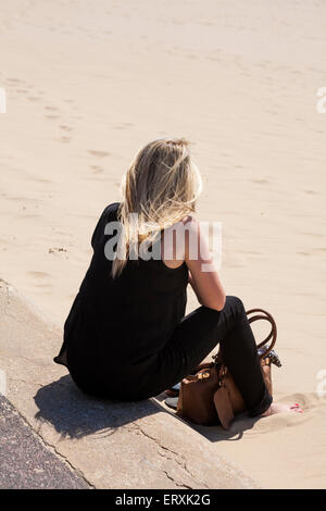 Jeune femme vêtue de noir de s'asseoir près de la plage de Bournemouth en Juin Banque D'Images