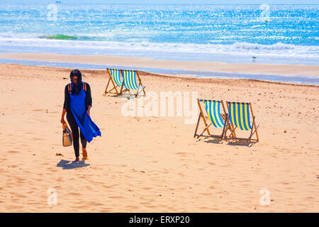 Effet pictural de femme marche vide passé transats sur une plage de Bournemouth à breezy day en Juin Banque D'Images