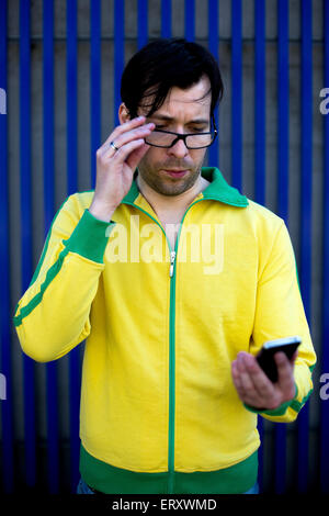 L'homme en jaune trikot en regardant son téléphone. Banque D'Images