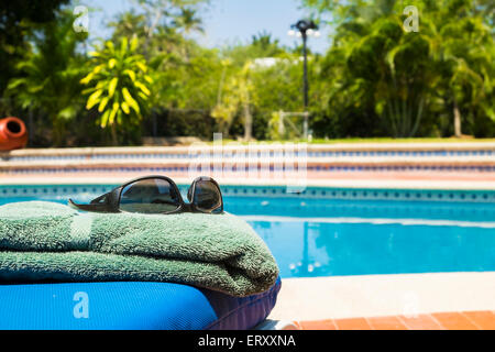 Jardin résidentiel avec piscine, serviette et lunettes Banque D'Images