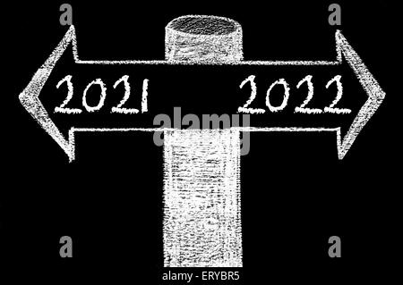 Flèches opposées à l'année 2021 en fonction de l'année 2022. Dessin à la main avec de la craie sur tableau noir. Choix de l'image conceptuelle Banque D'Images