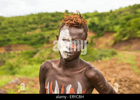 Jeune garçon de la tribu africaine Mursi avec traditionnellement peints en face du Parc National de Mago, en Ethiopie Banque D'Images