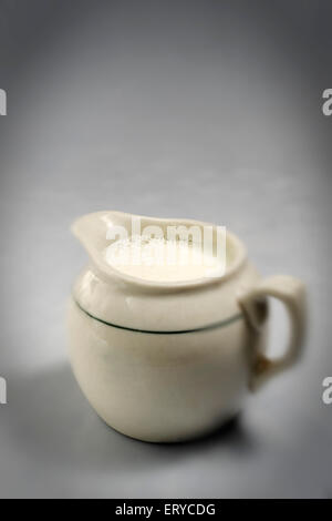 lait dans un pot en céramique sur fond gris Banque D'Images