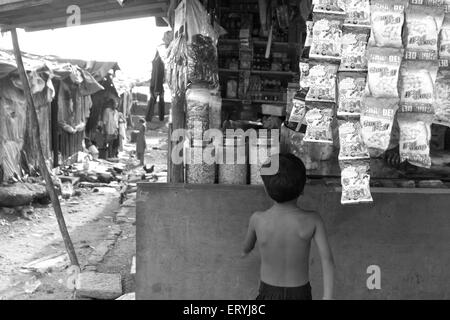 Enfant devant le bidonville malvani magasin ; Malad ; Bombay , Mumbai ; Maharashtra ; Inde , asie bidonvilles indiens Banque D'Images