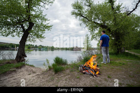 L'homme et de feu de forêt au printemps. Les charbons de feu. Crépuscule en Ukraine Banque D'Images