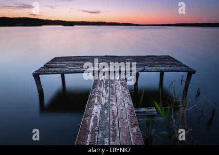 Petite jetée en bois sur grand lac au coucher du soleil en Ukraine Banque D'Images