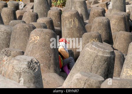 Homme assis entre des tétrapodes en béton , forme tétraédrique , Marine Drive , Bombay , Mumbai ; Maharashtra ; Inde , asie Banque D'Images