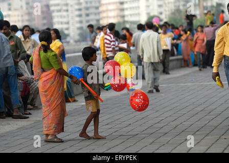 Jeune garçon avec sa mère vend des ballons colorés aux touristes se rendant sur Marine Drive dans Bombay Mumbai Banque D'Images