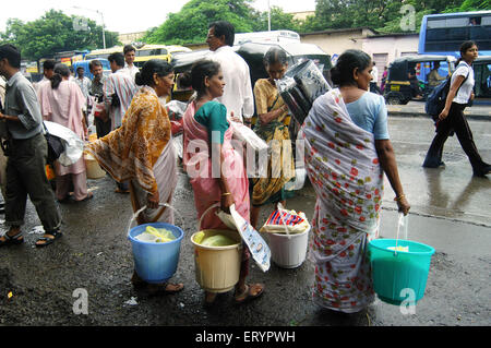 Pauvres avec des matériaux de secours, seaux, tapis, paquets de nourriture, Ghatkopar ; Bombay , Mumbai ; Maharashtra ; Inde , asie Banque D'Images