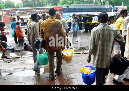 Pauvres avec des matériaux de secours, seaux, tapis, paquets de nourriture, Ghatkopar ; Bombay , Mumbai ; Maharashtra ; Inde , asie Banque D'Images