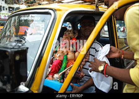 Les dévots transportant le dieu Ganesh idol en taxi sur ganpati ; festival ; Lalbaug Bombay Mumbai Maharashtra ; Inde ; 22 août 2009 Banque D'Images