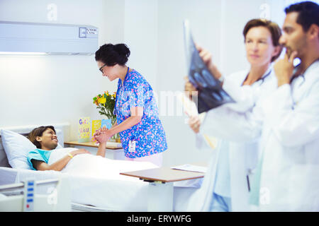 Nurse holding hands with patient in hospital room Banque D'Images