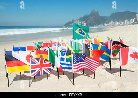 Drapeaux internationaux voler avec drapeau brésilien sur le sable contre une vue sur l'horizon de la plage d'Ipanema à Rio de Janeiro, Brésil Banque D'Images