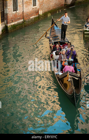 Venise, Italie - 24 avril 2013 : les touristes ride une gondole traditionnelle sur un petit canal. Banque D'Images