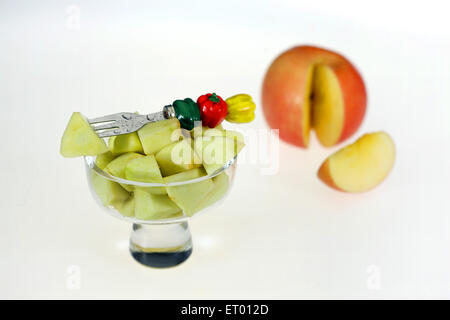 L'Apple Malus pumila morceaux dans un bol de fruits avec des fruits décoratifs et une fourche couper la tranche de pomme Banque D'Images