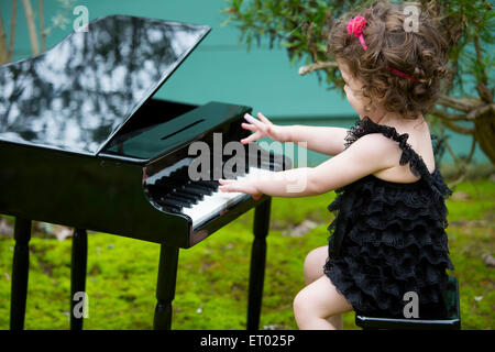 Petite fille jouant sur un piano jouet Banque D'Images