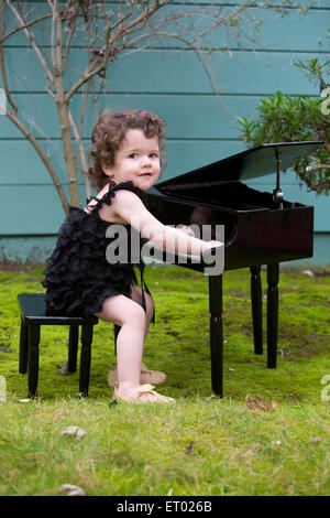 Petite fille jouant sur un piano jouet Banque D'Images