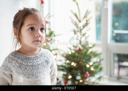 Wide-eyed girl looking up in front of Christmas Tree Banque D'Images