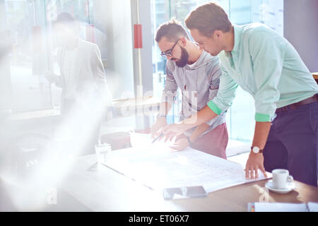 Architects reviewing blueprints in sunny office Banque D'Images