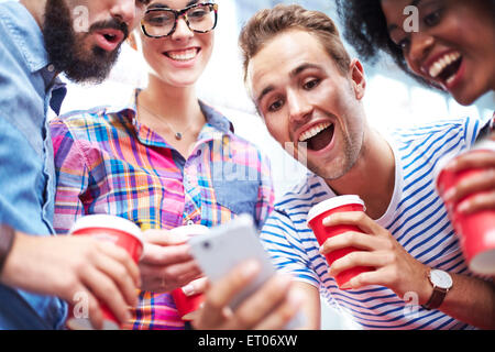 Les amis de rire et de boire du café autour de cell phone Banque D'Images