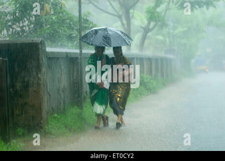 Deux femmes marchant sous un parapluie sous la pluie ; Kerala ; Inde mousson indienne Banque D'Images
