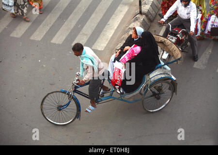 Deux femmes équitation sur tricycle rickshaw tiré par conducteur de pousse-pousse à Ranchi ville capitale de Jharkhand en Inde ; Banque D'Images