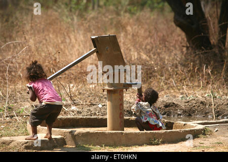 Les enfants ruraux indiens boivent de l'eau à partir de la pompe manuelle du village, Ranchi, Jharkhand, Inde, vie indienne Banque D'Images