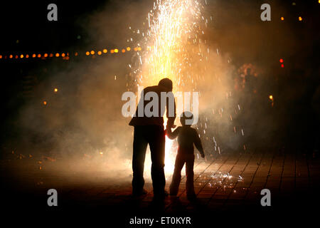 Père et fils éclatant pétards tout en célébrant Diwali, fête des lumières ; Deepawali à Marine Drive à Bombay Banque D'Images