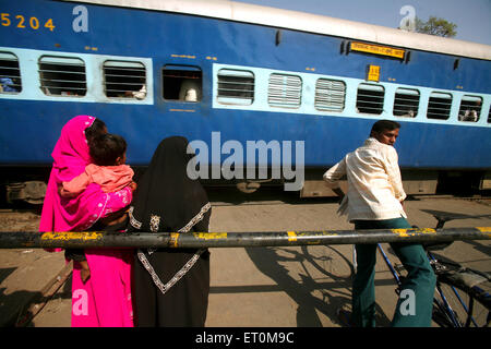 Les gens à un passage à niveau alors que les chemins de fer indiens express train railway crossing à Bhopal ; Madhya Pradesh en Inde ; Banque D'Images