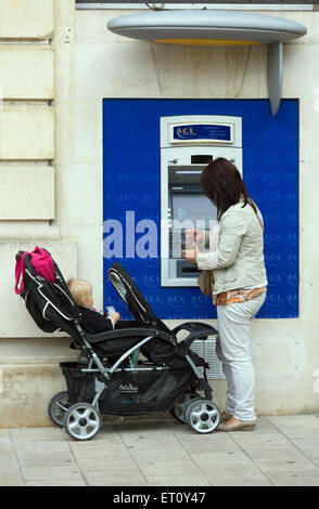 Reims, France, Femme avec enfant au guichet automatique de la Banque et Assurance LCL Banque D'Images