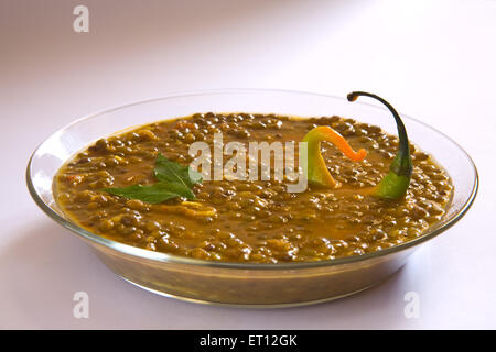 Le masoor dal indien gramme rouge soupe de lentilles garnir avec des feuilles de cari et le piment dans un bol de verre sur fond blanc 21 Avril 2010 Banque D'Images