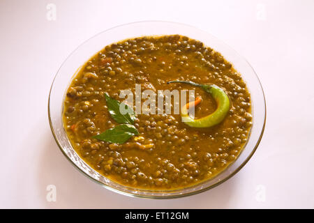 Le masoor dal indien gramme rouge soupe de lentilles garnir avec des feuilles de cari et le piment dans un bol de verre sur fond blanc 21 Avril 2010 Banque D'Images