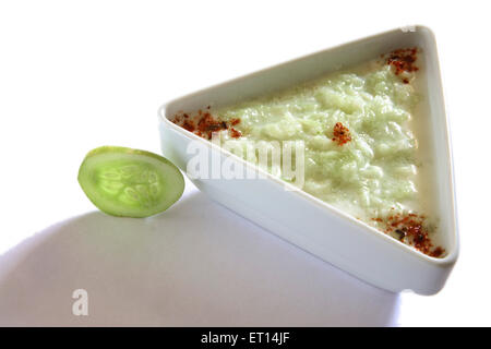 Salade de concombre et de légumes ; caillé kakri ka raita épicé avec la poudre de chili dans le triangle de la plaque sur le fond blanc Banque D'Images